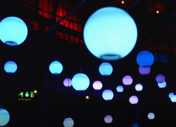 Installation of blue spherical lights hanging in a darkened warehouse.
