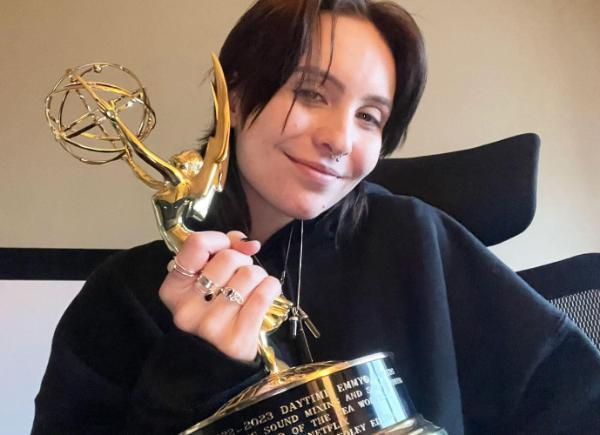 Person smiling and holding an Emmy award