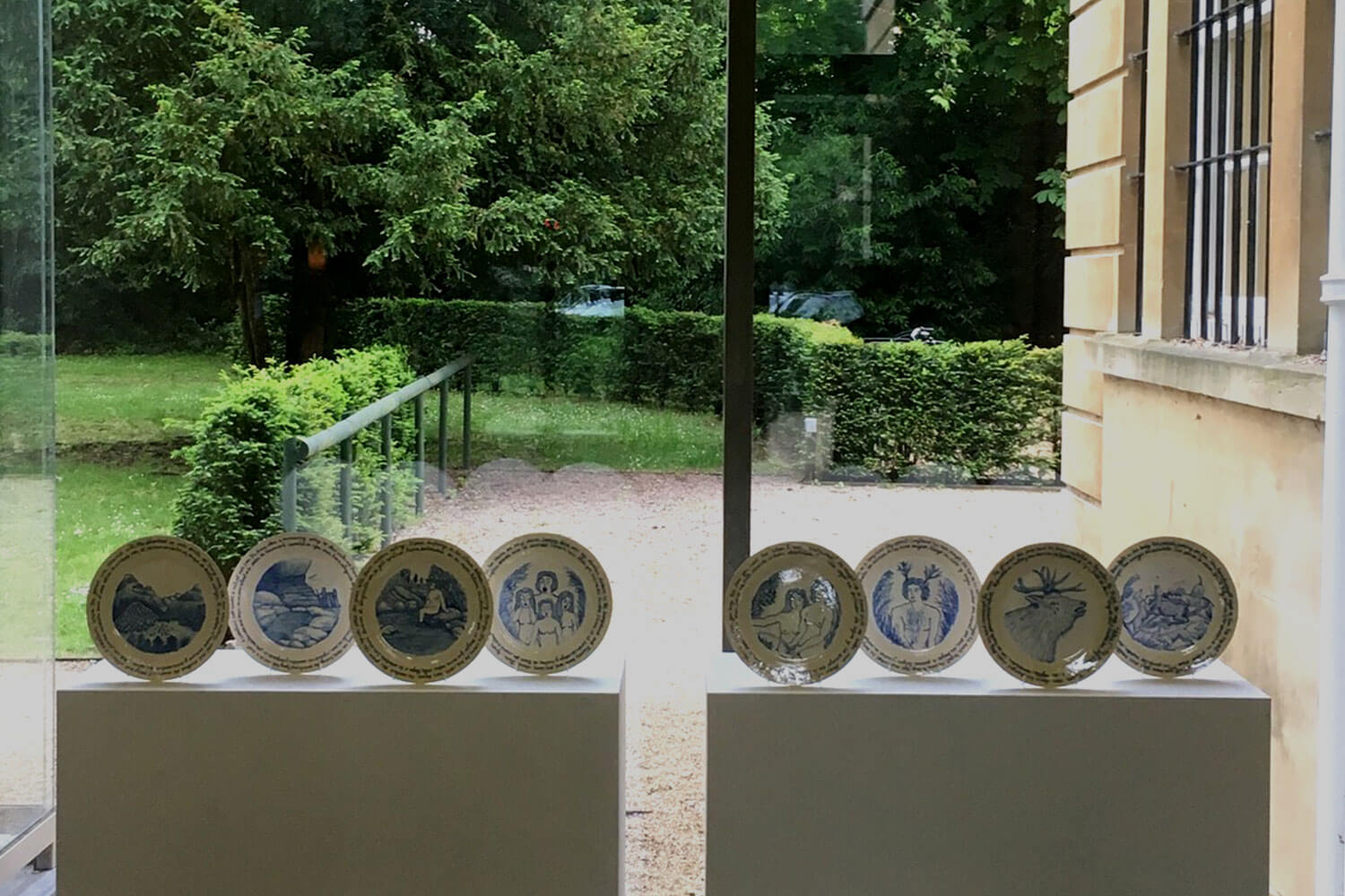A series of decorative plates displayed with a window in the background