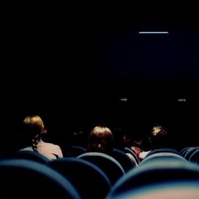 Cinema room in darkness with some people in the audience