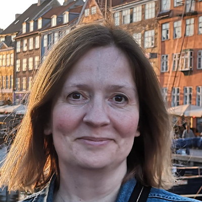 A Bath Spa University staff member smiles at the camera in a street in the evening.