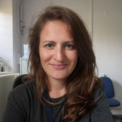 A smiling Bath Spa University staff member sitting in a white office.