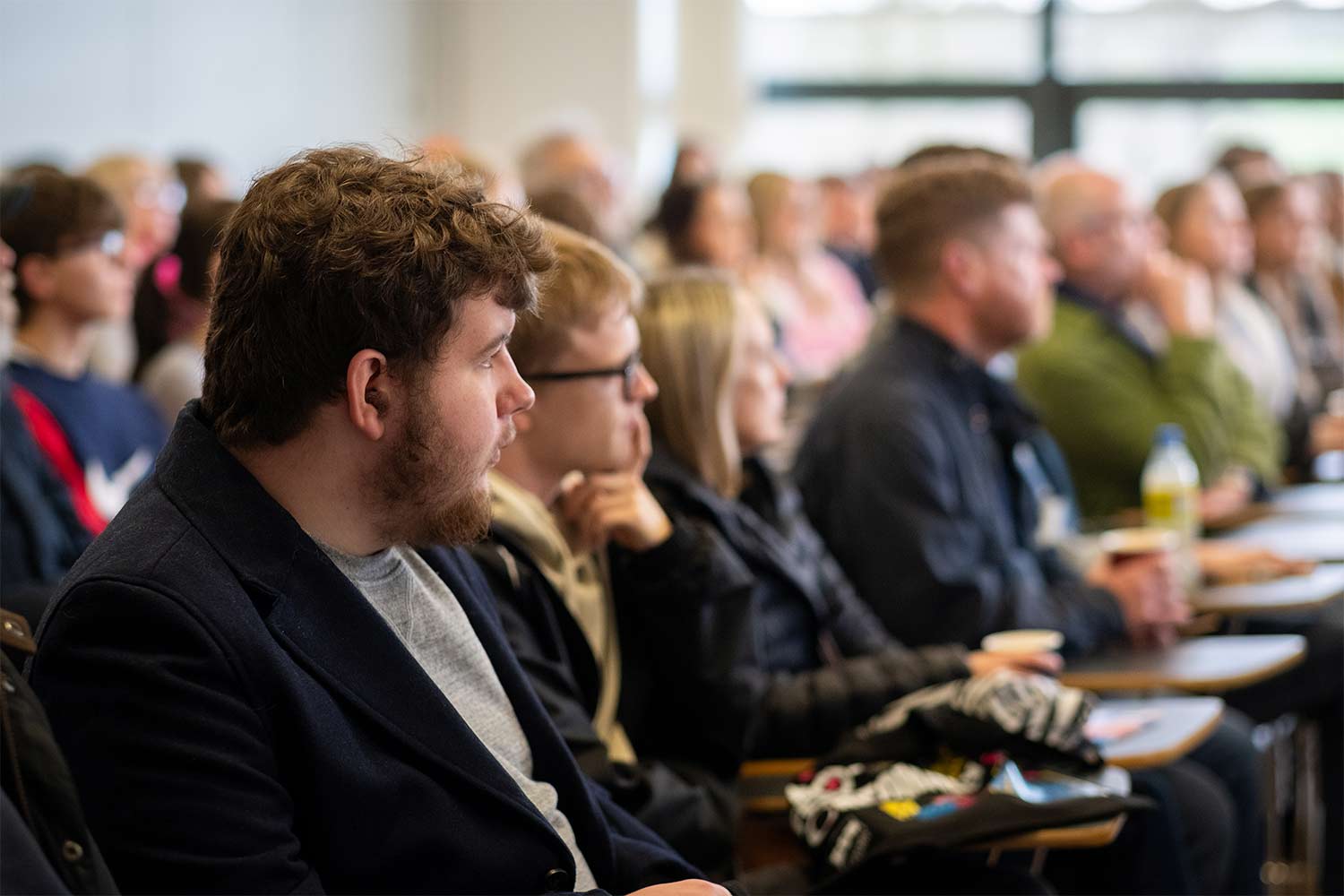 Photograph of group of people in a classroom environment intently watching something off screen