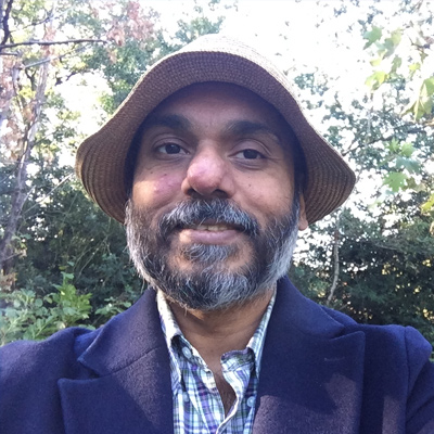 A smiling Bath Spa University staff member in front a background of sunny trees.