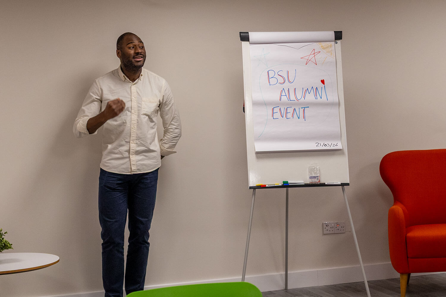 A man stood in front of a flipchart with the words Alumni Event on it