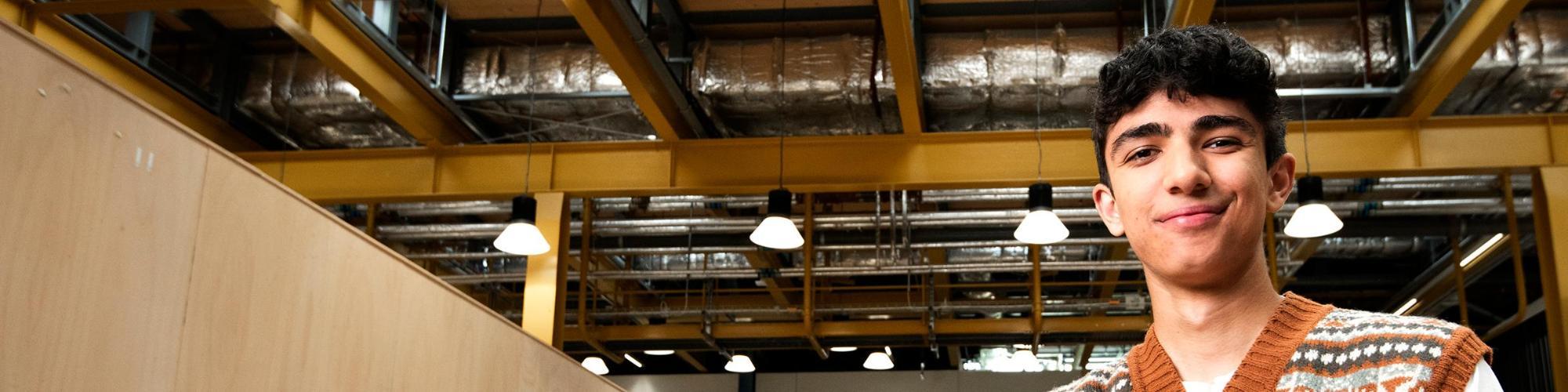 A student stands inside a modern industrial building