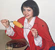 A younger Georgina Andrews eating corn on the cob, wearing a fashionable red jacket