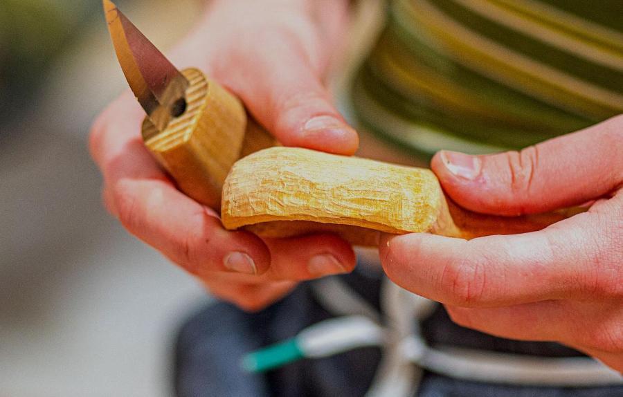 A close up of the hands of a student carving some wood