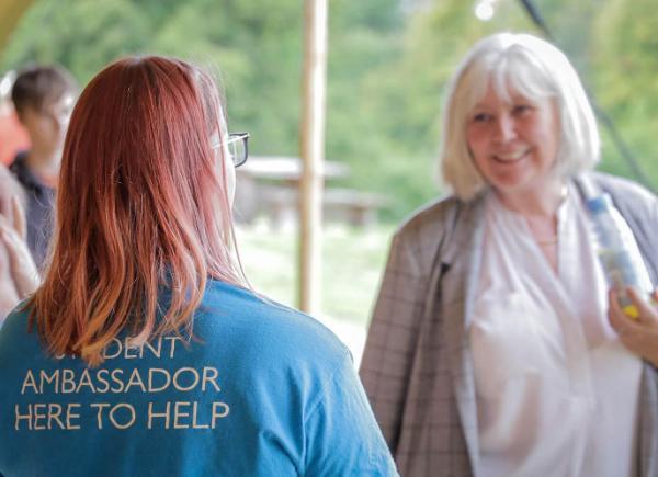 A student's supporter talking with a student ambassador on campus