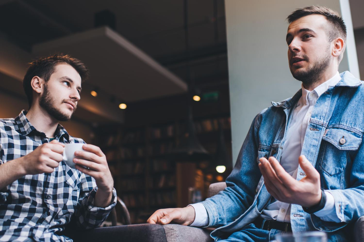 two men talking to each other at a coffee shop