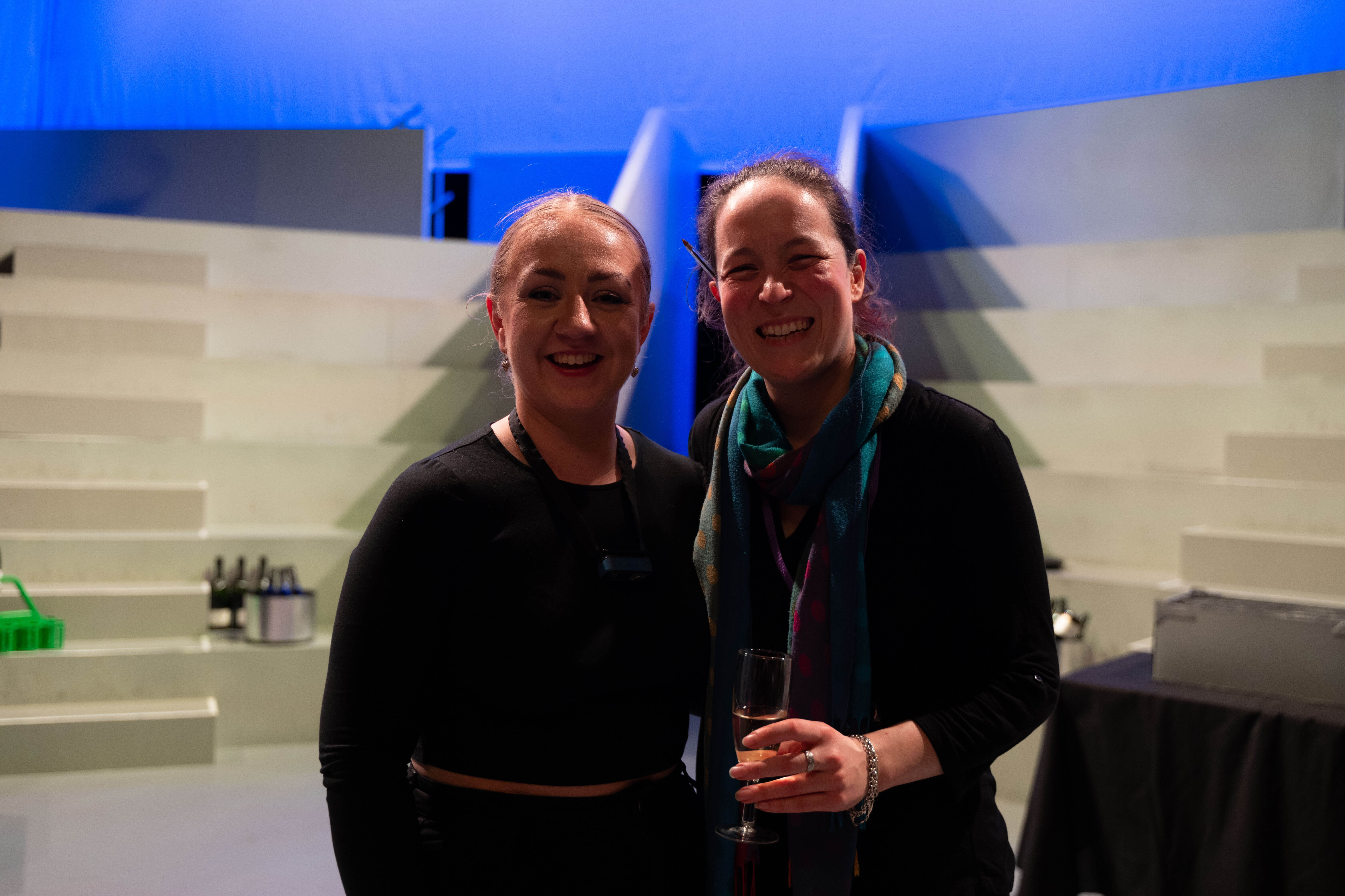 Two stage managers smiling stood next to each other