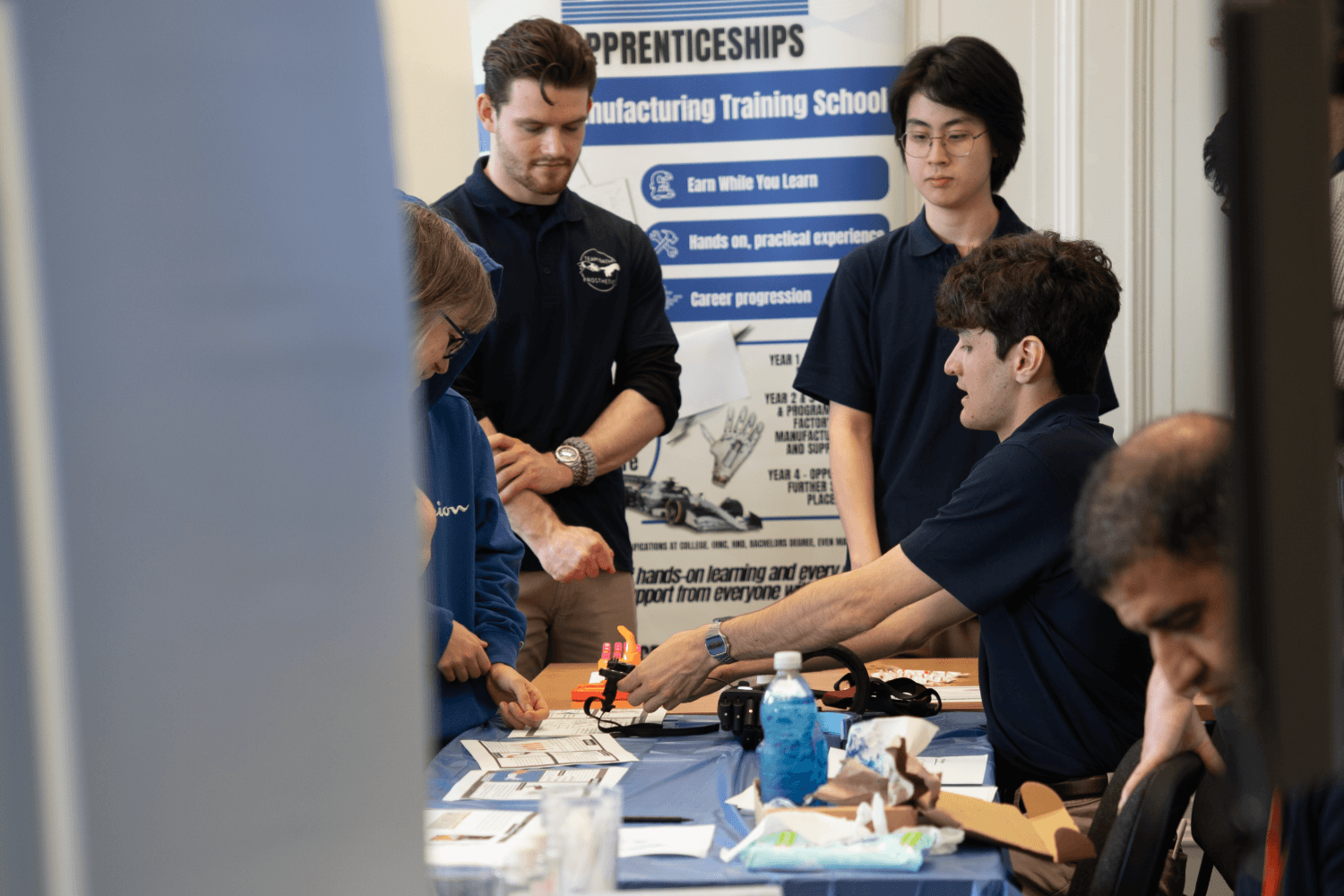 Two students showing two people how a piece of equipment works