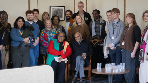 A group of people stood smiling with a photo of Haile Selassie behind them
