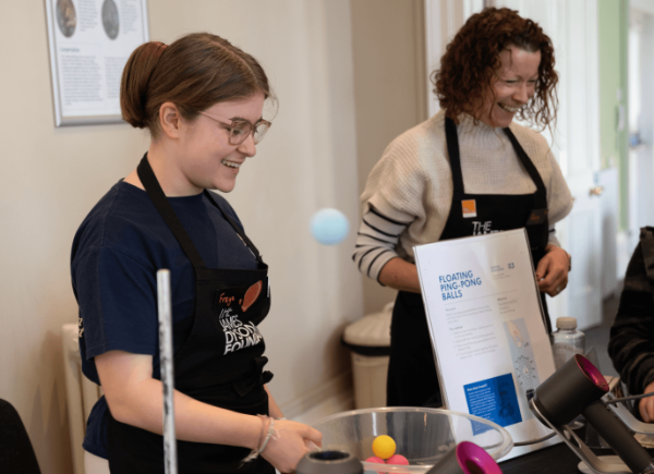 A students smiling and demonstrating a science experiment