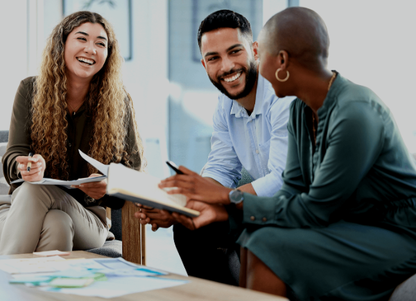 two women and a man sit smiling and talking to one another