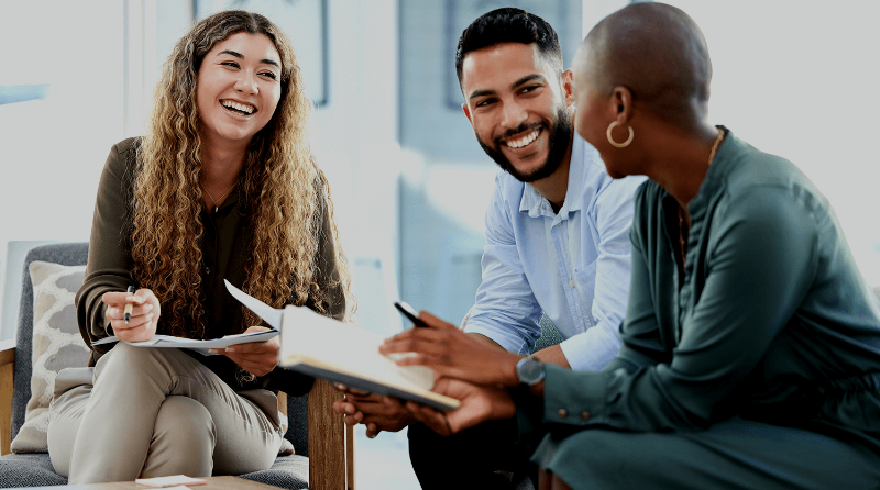 two women and a man sit together, smiling and talking to one another