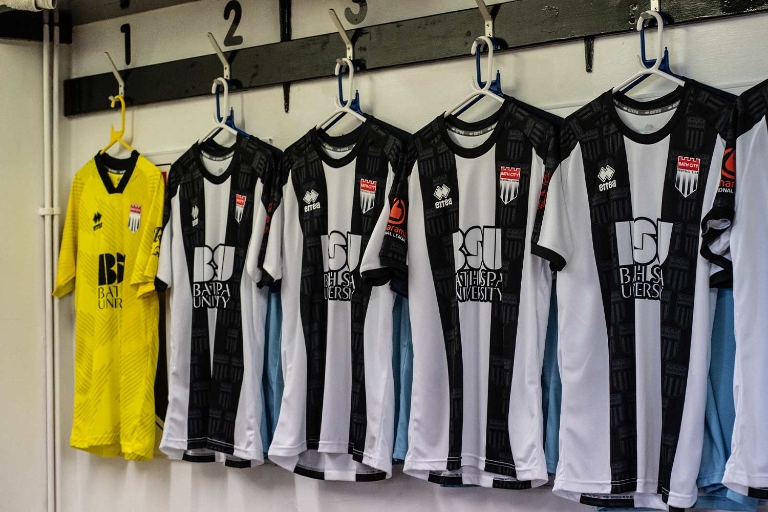A row of Bath City football shirts hanging in a changing room