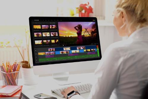 A woman is editing a video on a desktop computer, using a programme from the Adobe Creative Suite