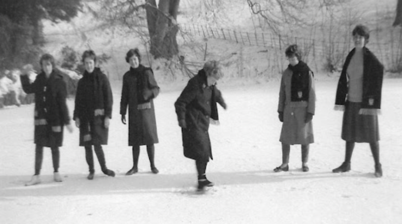 Black and white photo of a group of students playing with snow at Newton Park