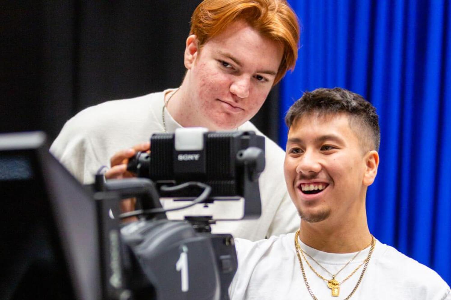 Two film students look through the viewfinder of a camera