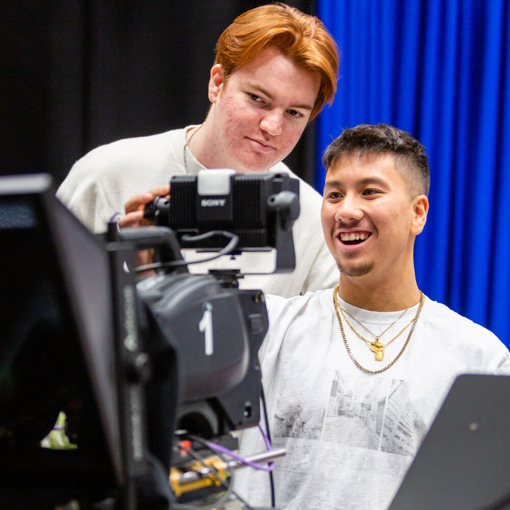 Two students checking film equipment in our TV studio