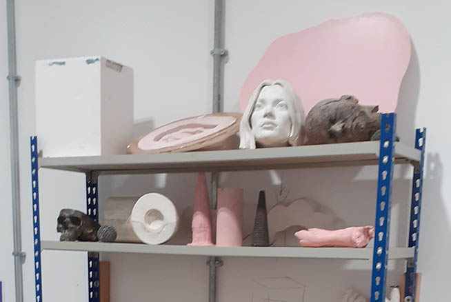 A shelf with various sculptures and clay works displayed