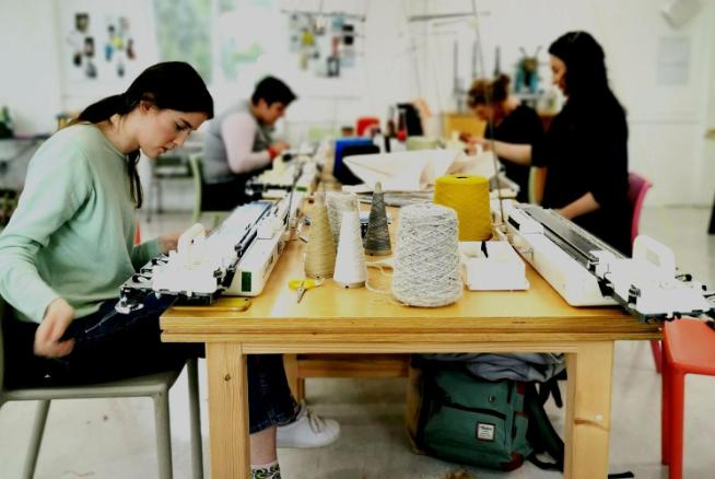 Students working at a crafting table with yarn