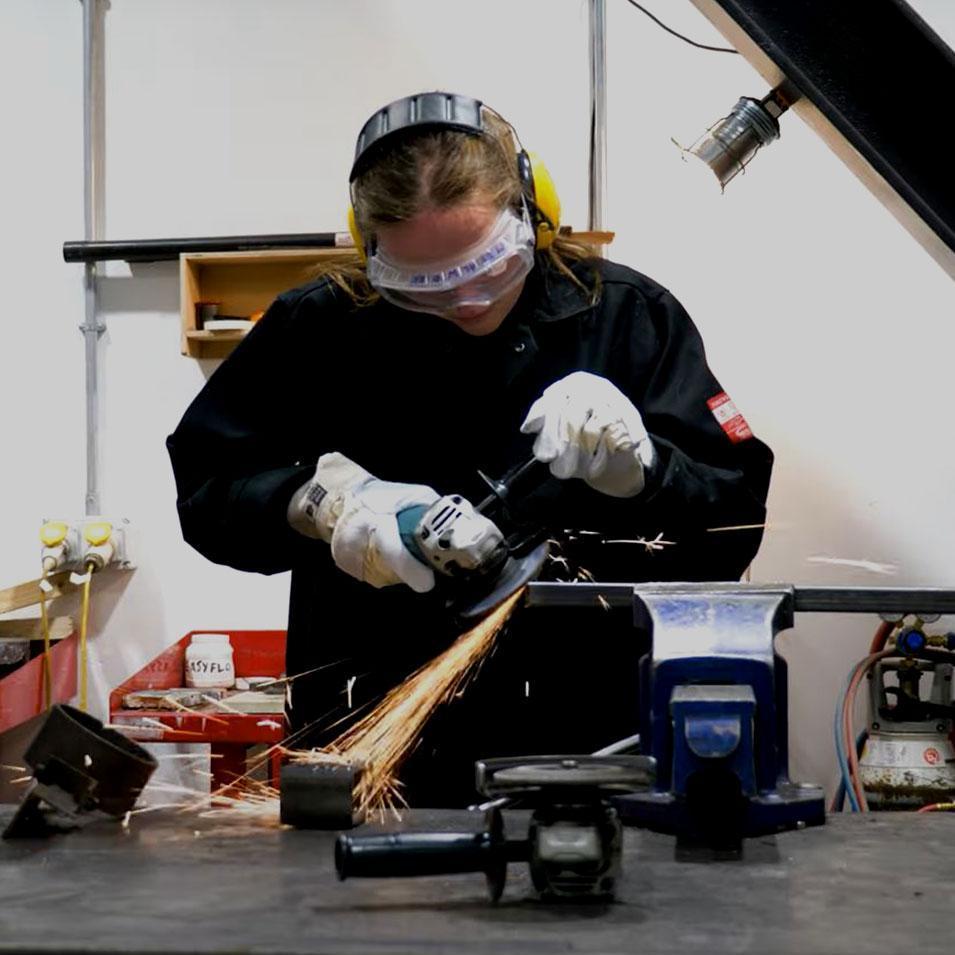 Student using an angle grinder with sparks flying