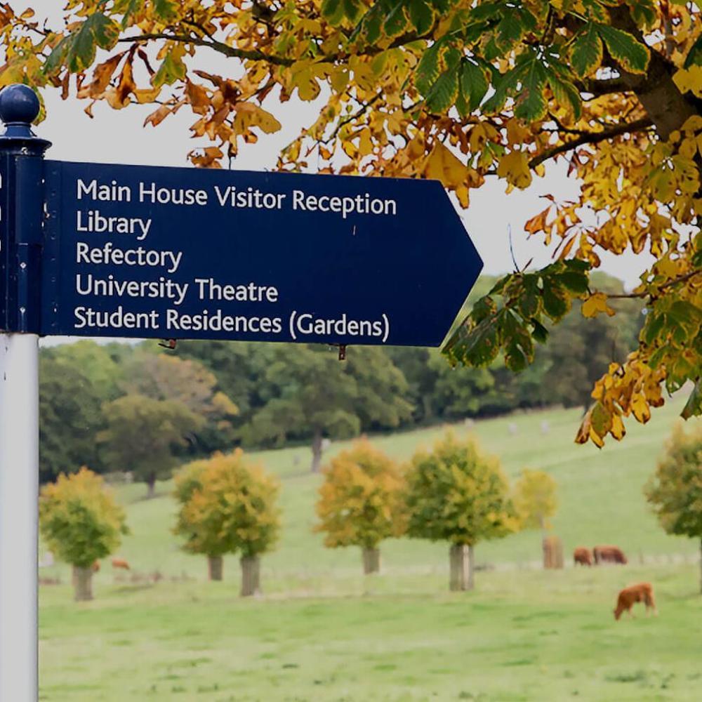 Campus sign with fields and cows in the background