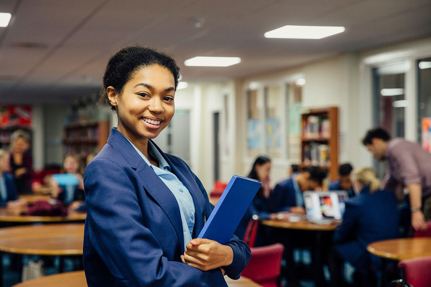 Confident school pupil holds her books in her classrom