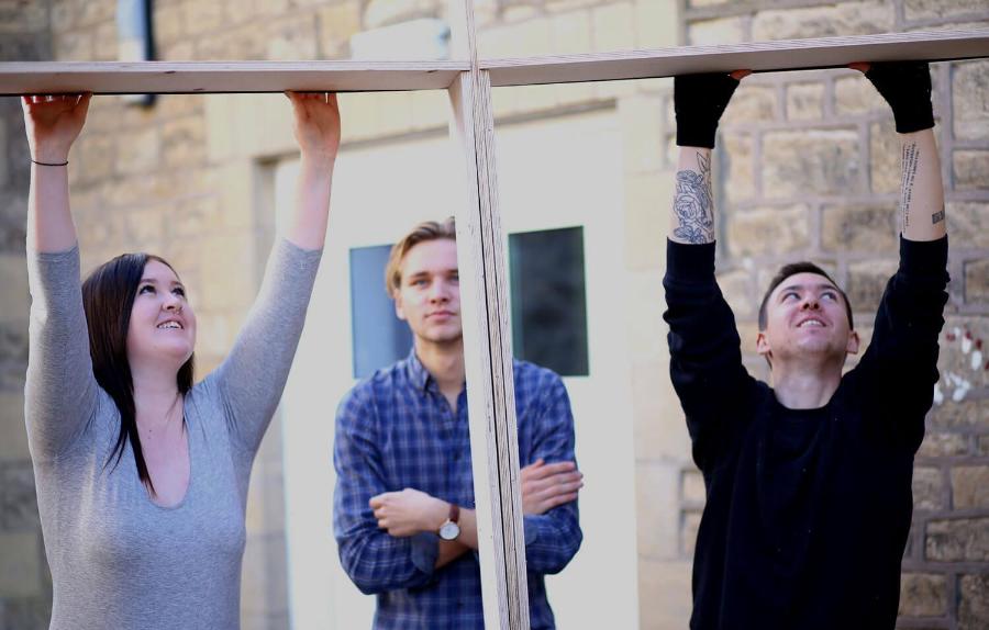 Three students building a wooden frame