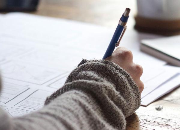 Person holding a pen and writing notes