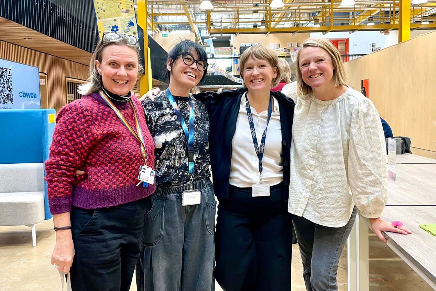 Four people stand side by side smiling at the camera in Locksbrook Campus.