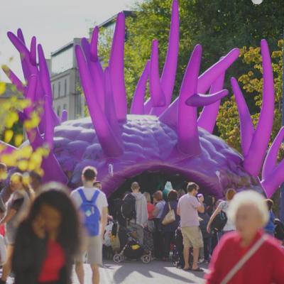 Purple inflatable dome with lots of people walking by 