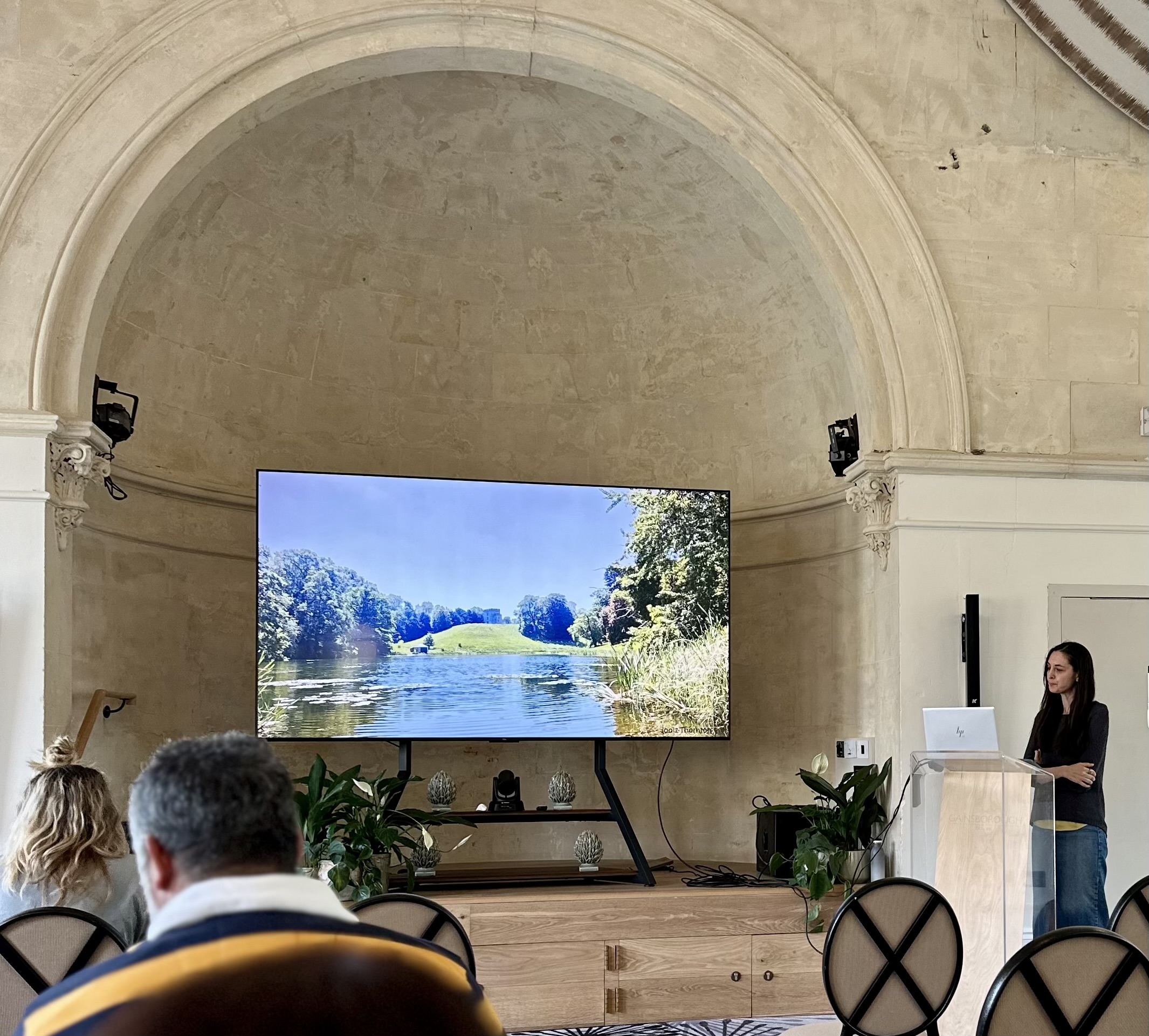 A TV screen in front of an audience and speaker