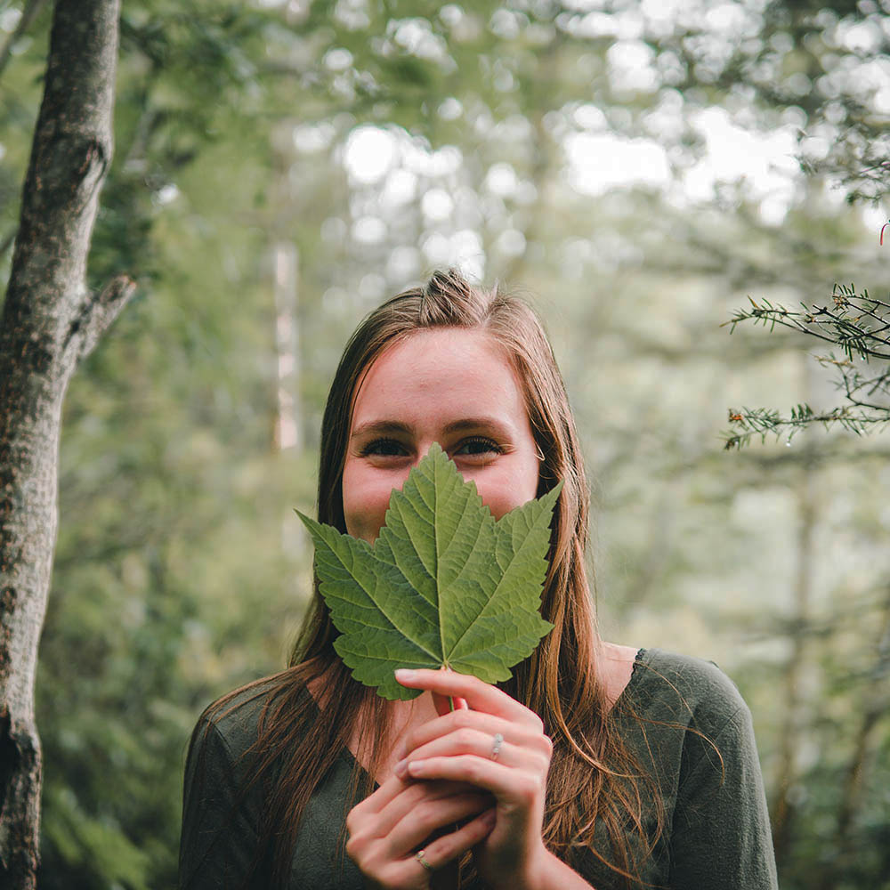 A shy person covering their face with a large leaf