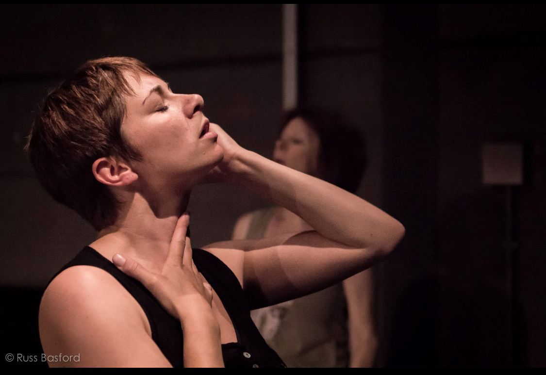 A person leans their head back and reaches their hand to their face