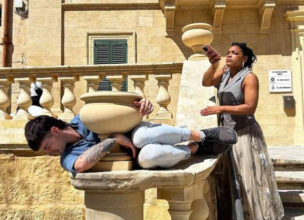 Two people moving around outdoor furniture