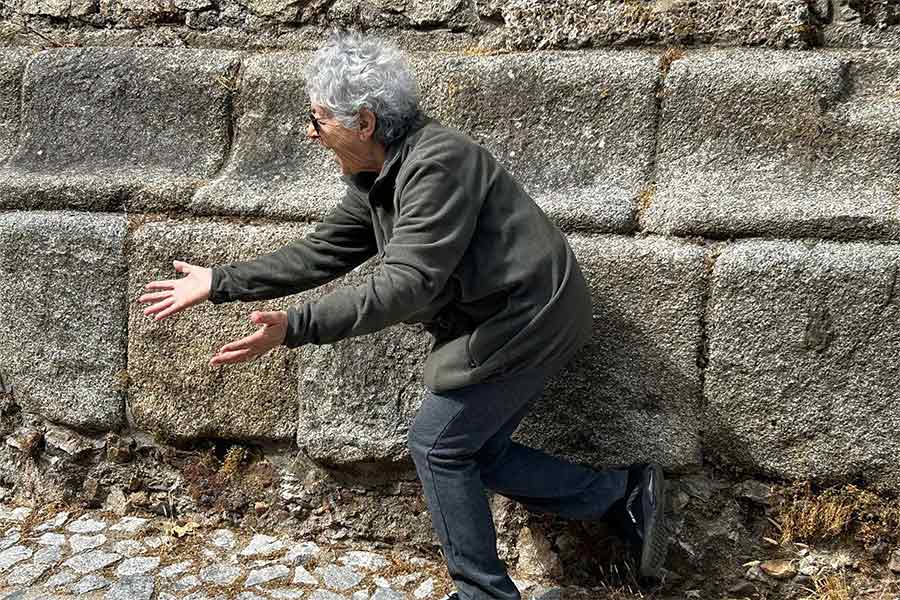 Person in grey dancing against a wall