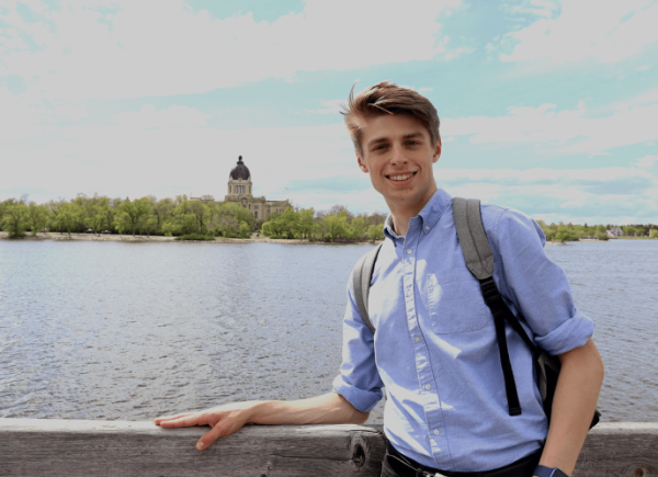 student smiling stood on a bridge overlooking a river