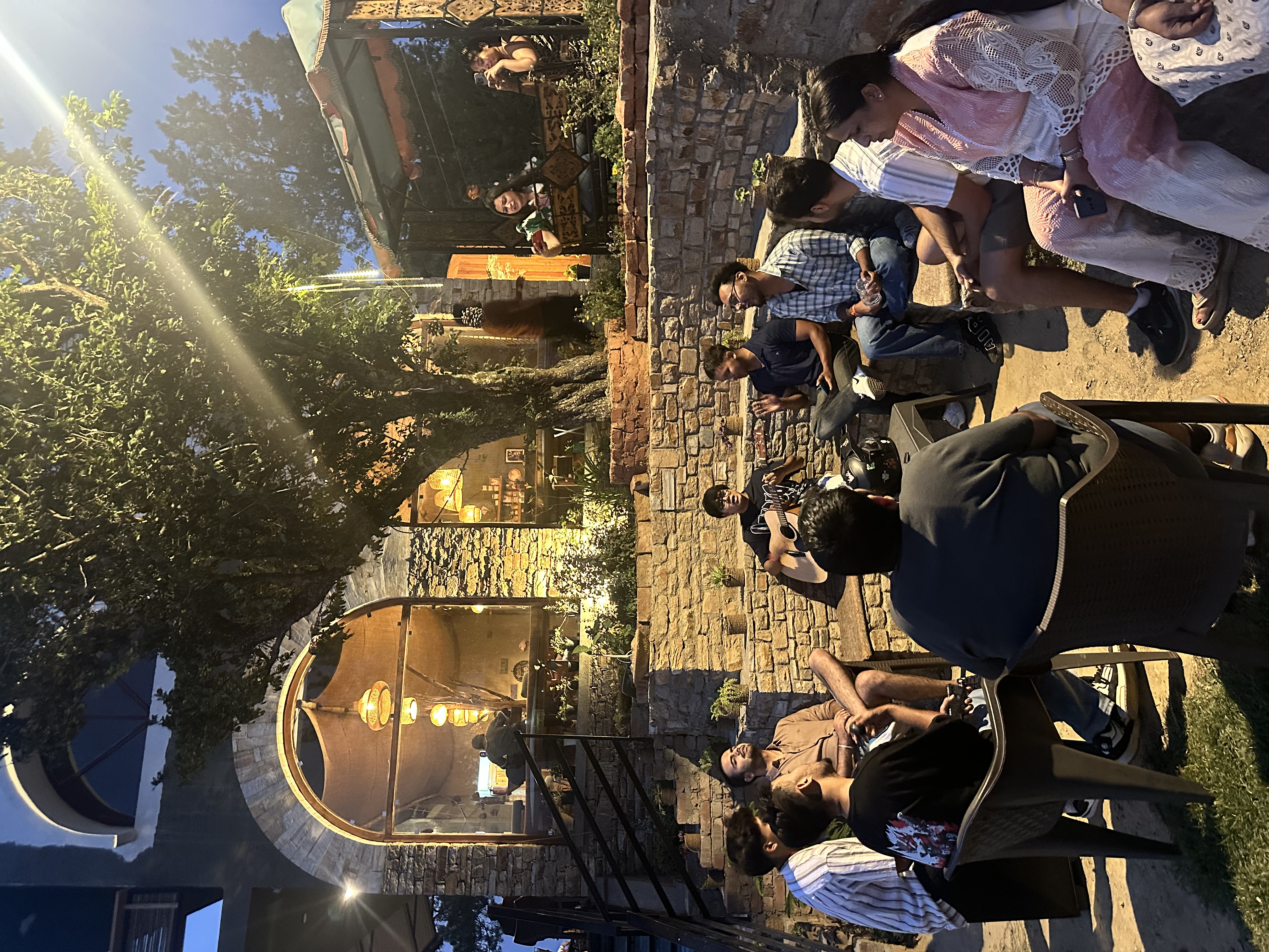 A group of people sitting around outside at night playing musical instruments