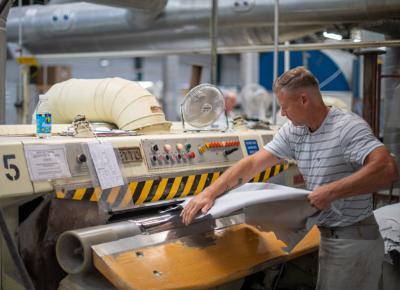 An image showing a worker shaving a sheet of material using a machine