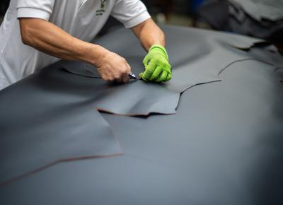 An image showing a worker trimming a sheet of leather