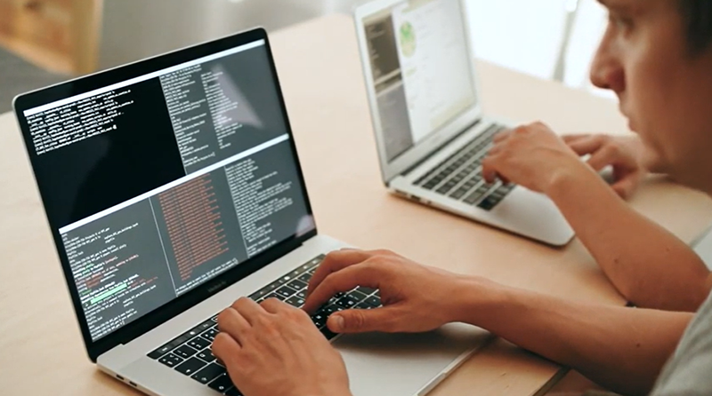 Computing students typing on laptops and looking at code