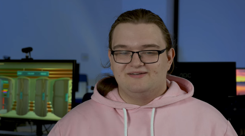 A student wearing glasses and a pink hoodie talks about Games Development.