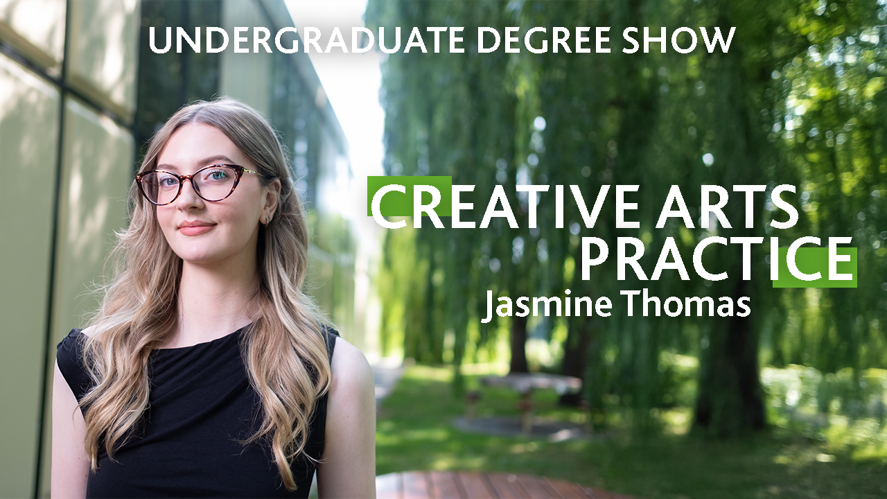 A person with long blonde hair and dark glasses stands outside a building surrounded by willow trees