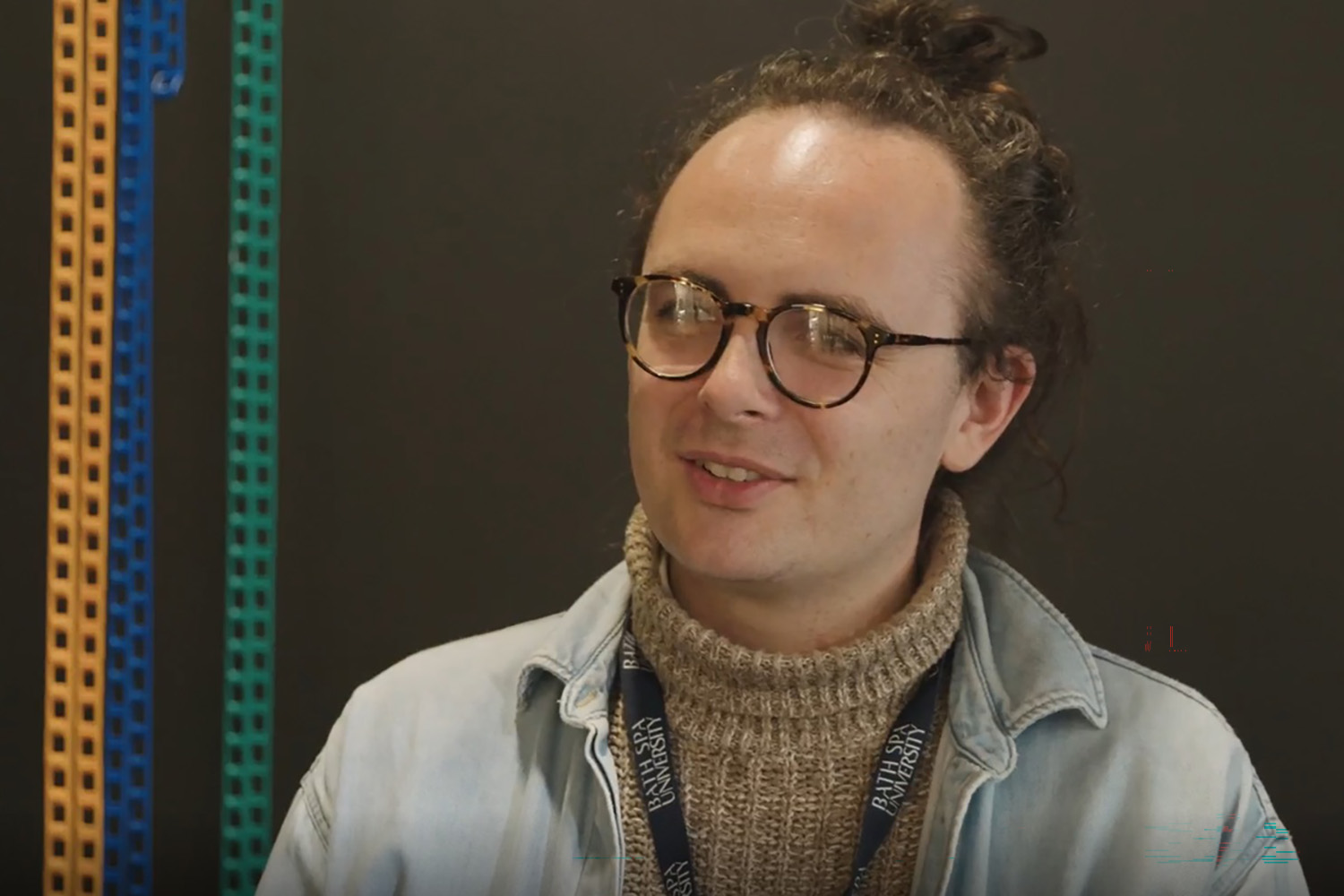 A Bath Spa programme leader being interviewed against a dark background.