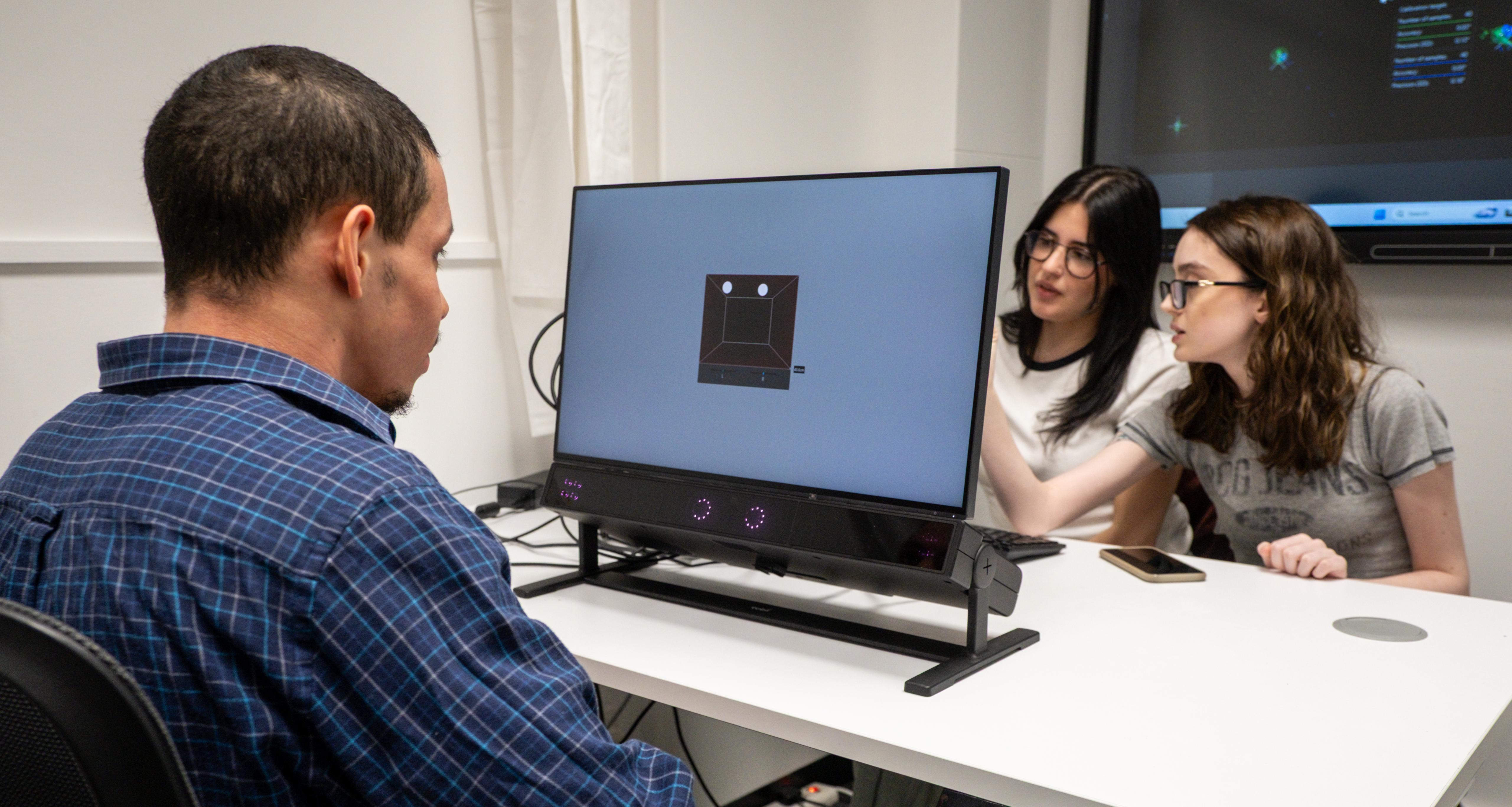 Three students sit at a desk to complete a practical psychology task