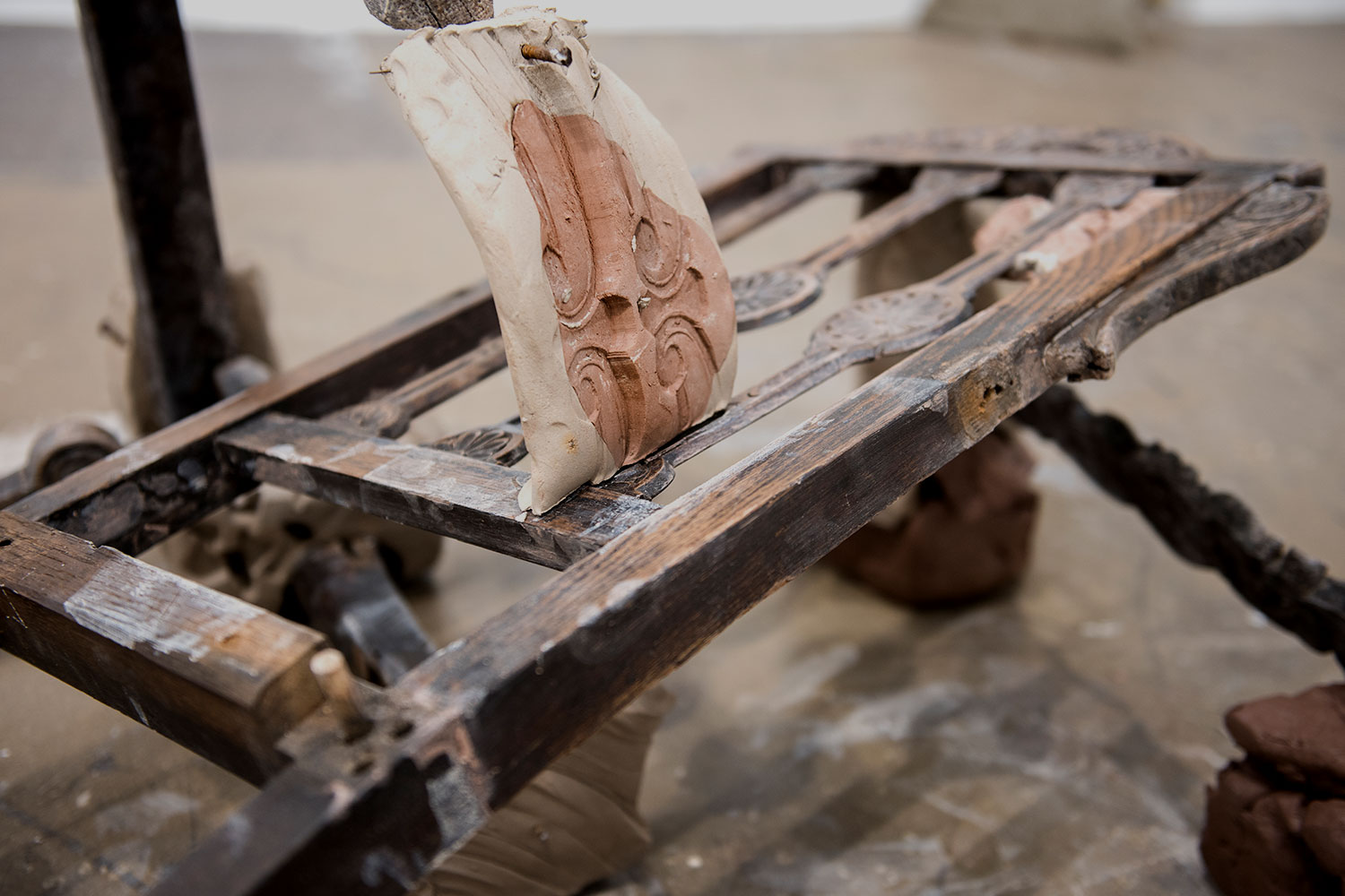 An artwork in progress featuring an old wooden chair and some clay