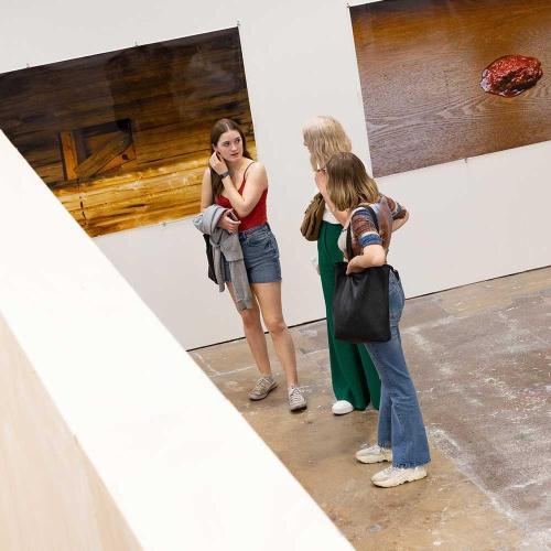 Three girls stood looking at artwork in a blank exhibition room